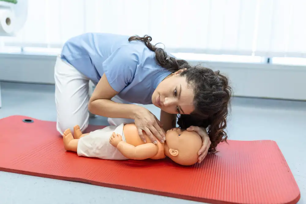 A woman practising paediatric CPR on a dummy on the Paediatric First Aid course with 4JH.