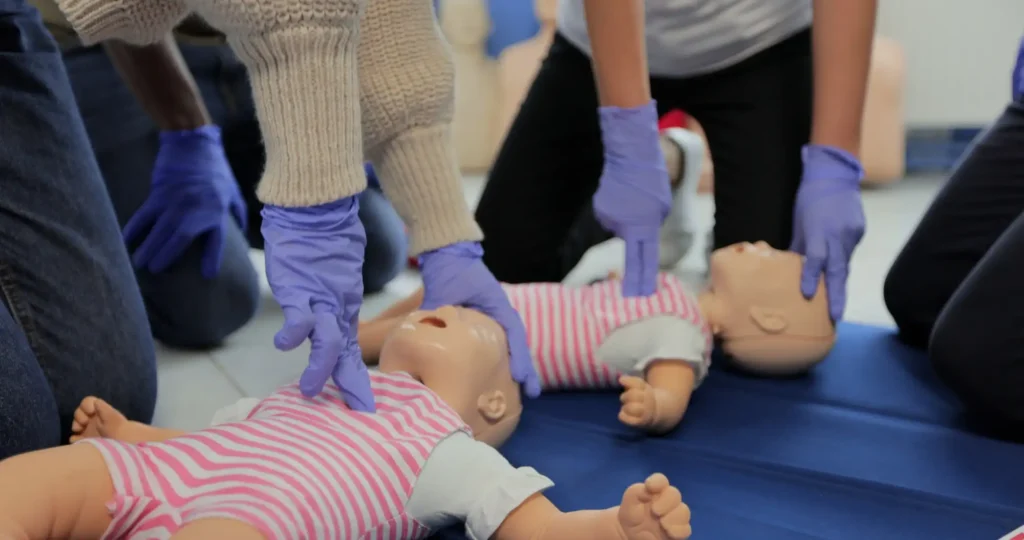 Two child resuscitation dolls being used to train a class in paediatric first aid.