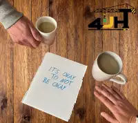 A piece of paper with "It's ok to not be ok" written on it and hands looking like they are going to hold each other to show the mental health first aid course that 4JH runs.
