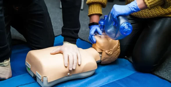 A 4JH instructor teaching someone how to administer medicinal oxygen to a dummy.