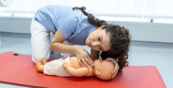 A woman practising paediatric CPR on a dummy on the Paediatric First Aid course with 4JH.